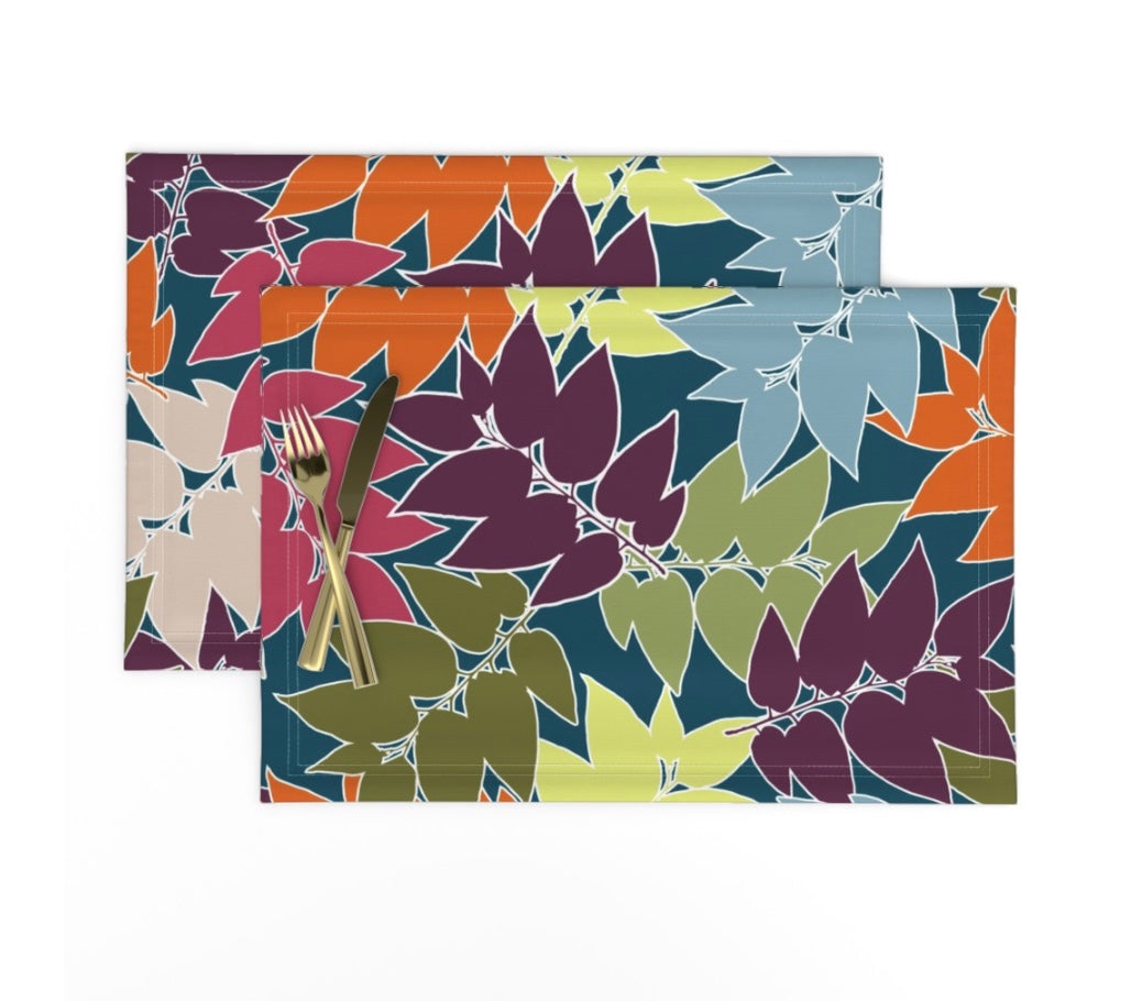 Two placemats with multi colored leaf pattern and silverware