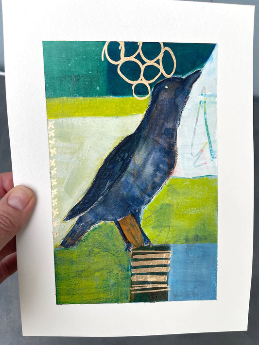 hand-held crow painting showing the glint of gold marker embellishments