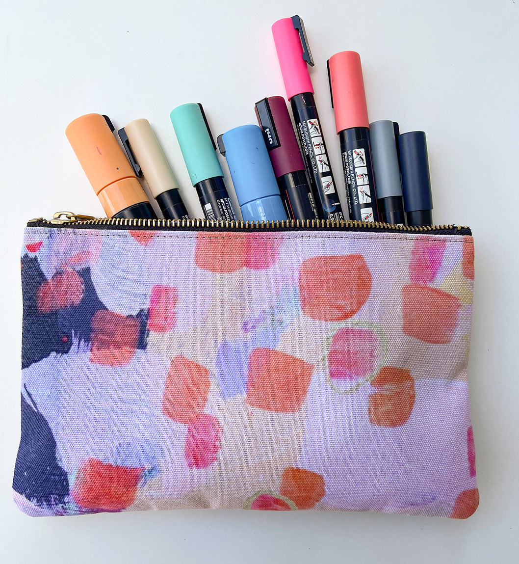 side view of pale pink orange and navy zipper pouch filled with markers