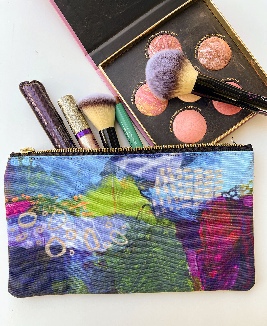 flat lay of navy and magenta zipper pouch with make up and brushes